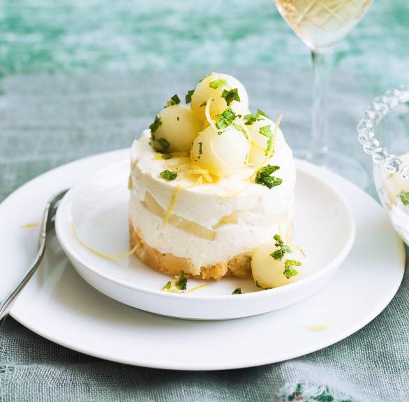 Törtchen aus Joghurt-Sahne-Creme und Melone auf einem Dessertteller dekoriert mit Minze