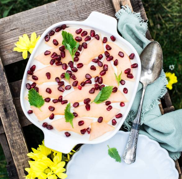 Tiramisu auf einem Gartnetisch getoppt mit Melonensplaten und Granatapfelkernen