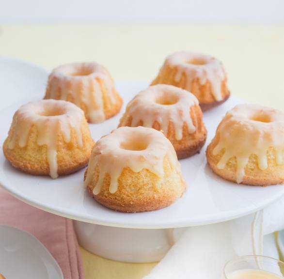 Mini-Gugelhupfe auf einer Tortenplatte, dahinter Shotgläser mit Eierlikör