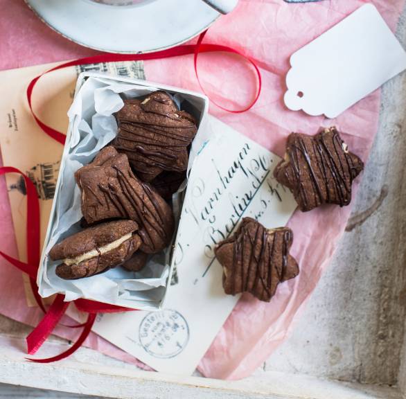 Sternförmige Mokkaplätzchen mit Füllung auf einem weihnachtlich dekorierten Kaffeetisch