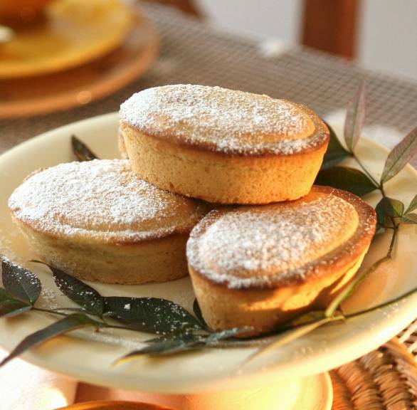 Drei Pasticciotto Leccese auf einem Teller, eines halbiert mit Blick auf die Cremefüllung