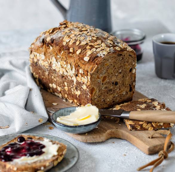 Selbstgebackenes Müslibrot mit Haferflocken angeschnitten auf einem Holzbrett