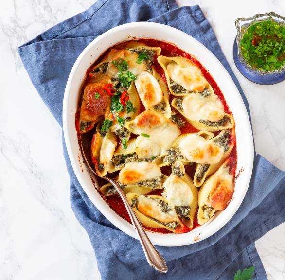 Überbackene Conchiglioni mit Ricotta-Grünkohl-Füllung in einer Auflaufform auf einem Tisch