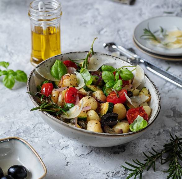 Nudelsalat aus Gnocchetti mit Antipasti aus gebackener Zucchini, Tomaten und Parmesan in einer Schüssel