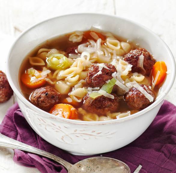 Nudelsuppe mit Einlage aus Rinderhackbällchen in einem Suppenteller, daneben einzeelne Hackfleischbällchen
