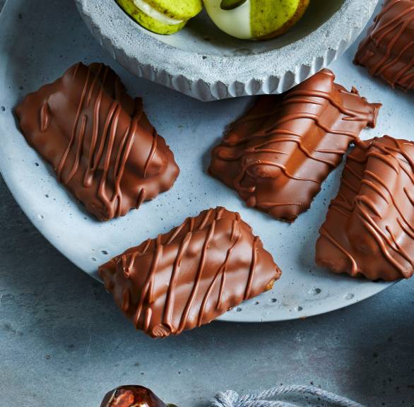 Selbst gemachte Nougat-Plätzchen mit Marzipan, Nüssen und Likör neben anderen Plätzchensorten auf einem Teller