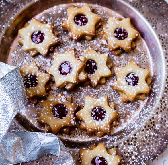 Haselnussplätzchen-Sterne mit Johannisbeerfüllung auf einem Plätzchenteller