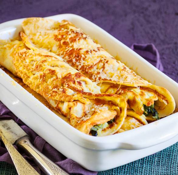 Ofenpfannkuchen in einer Auflaufform gefüllt mit Spinat und Gorgonzola