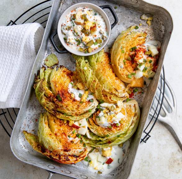 Gebackene Wirsingsplaten auf einem Backblech getoppt von gehackten Eiern und Kräuter-Joghurt-Creme