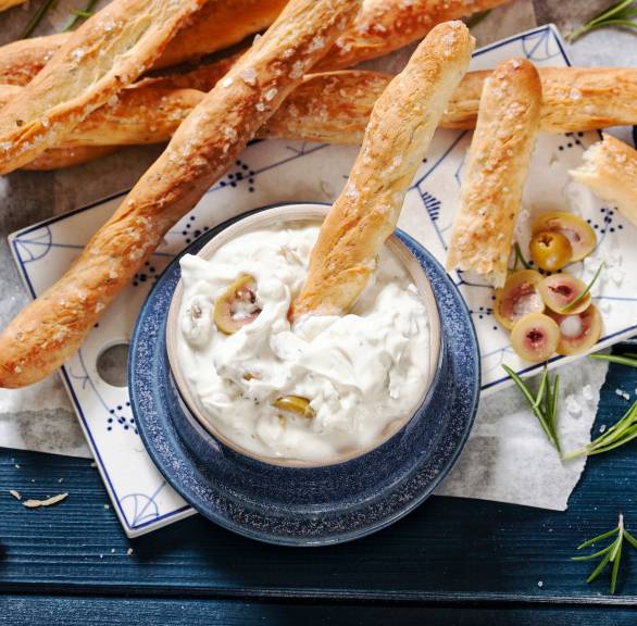 Olivendip mit Ziegenkäse und Joghurt in einer Schale, serviert mit Grissini