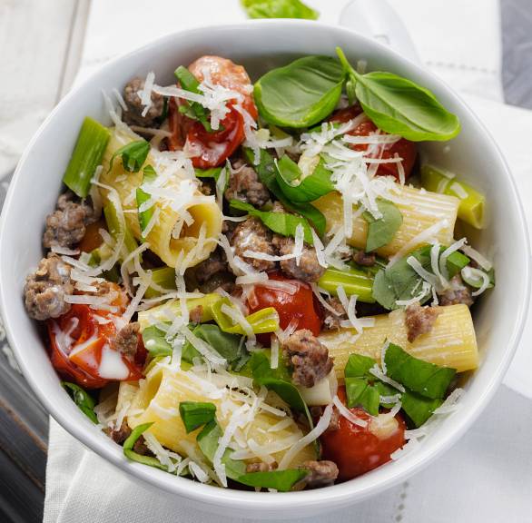Topf mit One-Pot-Pasta mit Lammhackfleisch, Tomaten und Sahnesauce auf einem Tisch