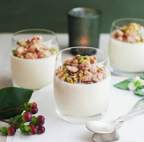 Joghurt-Mousse in drei Dessertgläsern getoppt mit Amarettini-Pistazien-Streuseln auf einem weihnachtlich dekorierten Tisch