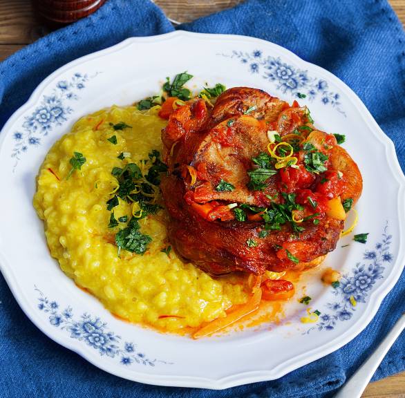 Kalbfleisch mit Sauce auf einem Teller, daneben Safranrisotto