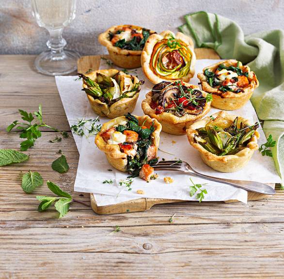 Ostermuffins mit verschiedenen herzhaften Füllungen auf einem Holzbrett