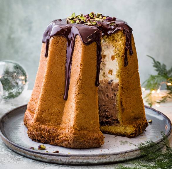 Pandoro Weihnachtskuchen angeschnitten auf einem runden Teller, dahinter Weihnachtsdeko