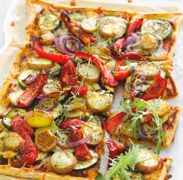 Vegane Pizza mit Zucchini, Paprika und Kartoffeln angeschnitten auf einem Backblech
