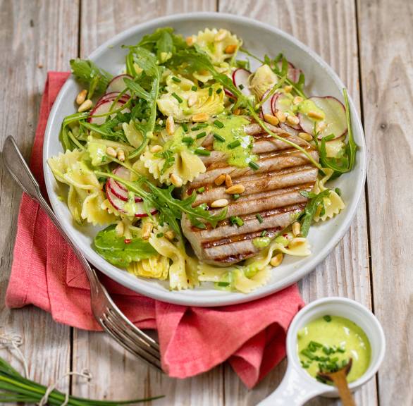 Pastasalat und Thunfischsteak vom Grill auf einem Teller, daneben Pesto
