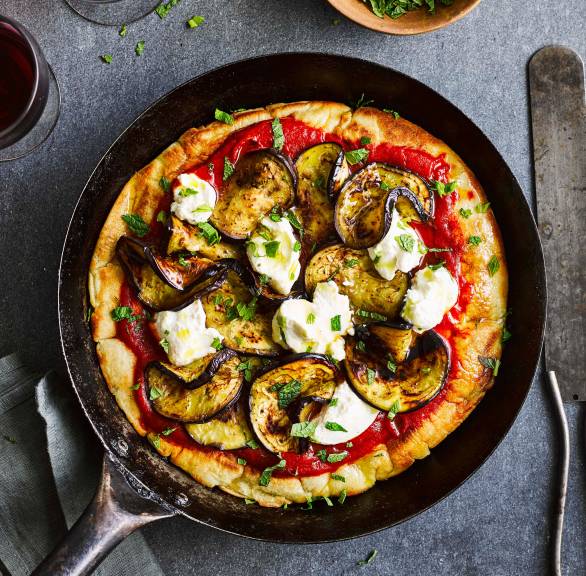 Pizza in einer Pfanne belegt mit Aubergine, Ricotta und Minze