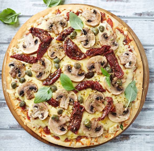 Runde Pizza Funghi auf einem Pizzabrett garniert mit frischem Basilikum