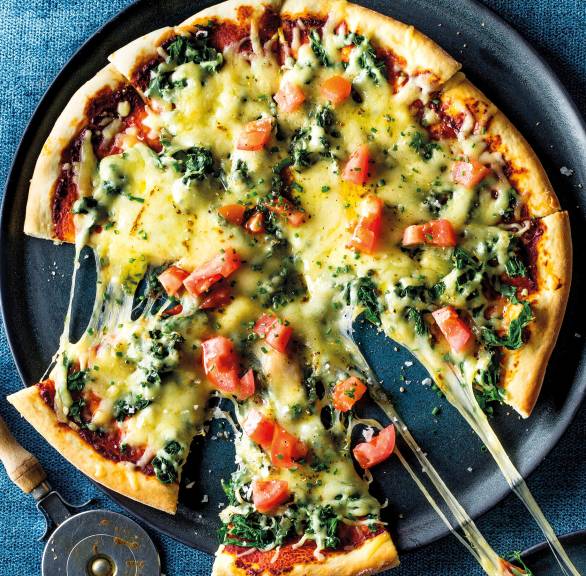 Vegetarische Mangold-Pizza angeschnitten auf einem Pizzateller