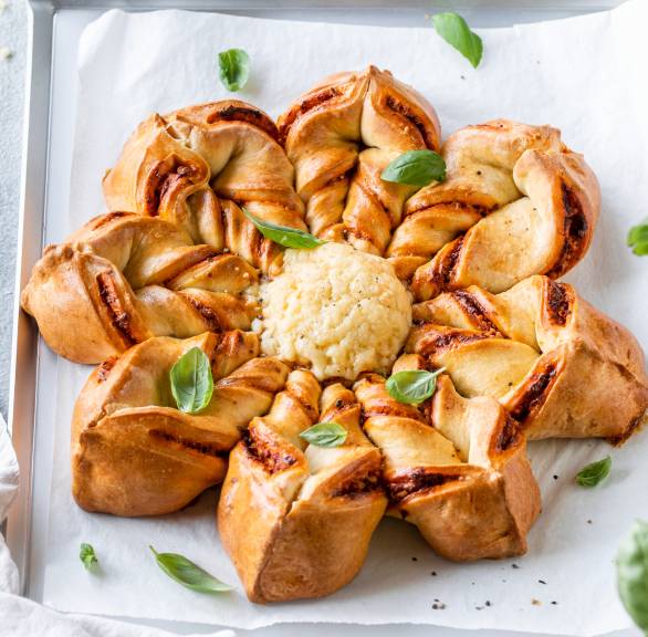 Selbstgebackene Pizzablume mit geschmolzenem Mozzarella in der Mitte auf einer Servierplatte