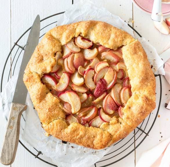 Eine gebackene Pfirsich-Crostata mit Polenta-Teig auf einem Kuchengitter auf einem Holztisch
