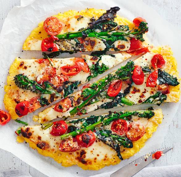 Runde Polentapizza mit Gemüse und Mozzarella in Streifen geschnitten auf einem Teller