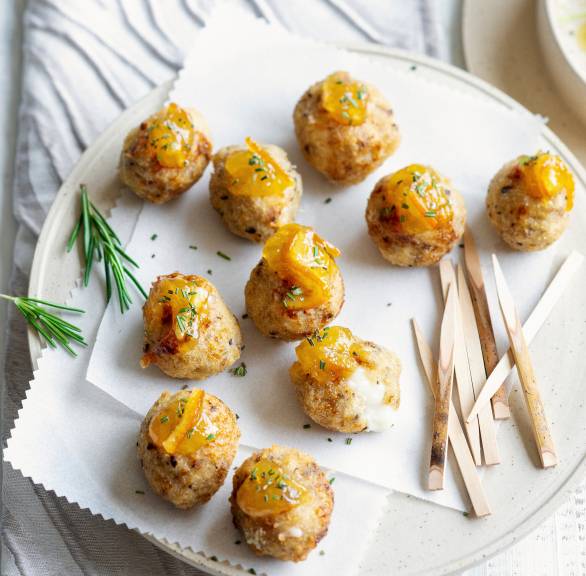 Frittierte Brot-Käse-Bällchen mit Provola-Kern mit einem Klecks Orangenmarmelade auf einer Servierplatte