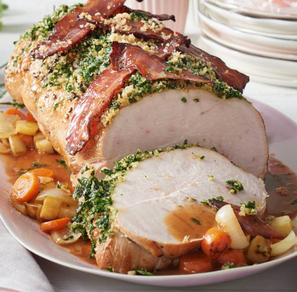 Putenbraten mit Kräuterkruste und Pancetta auf einer Platte