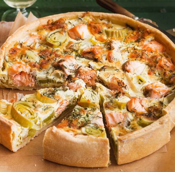 Lachs-Quiche angeschnitten auf einem Holzbrett