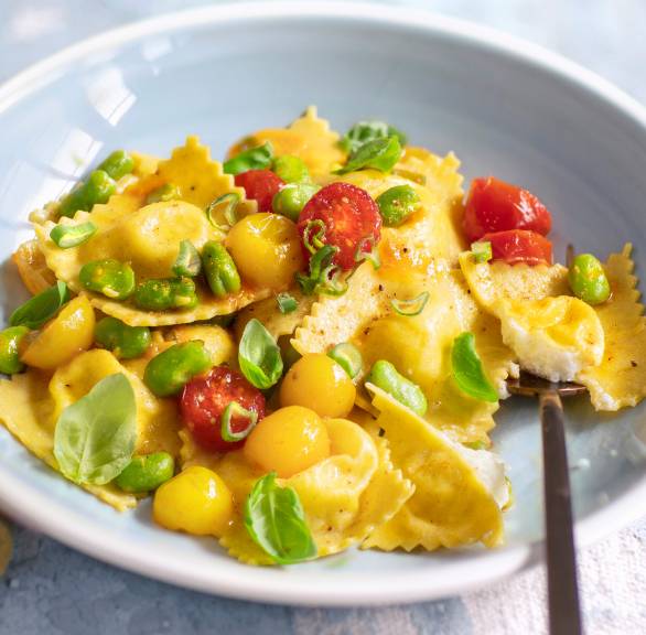 Selbst gemachte Ravioli auf einem Teller getoppt von Tomaten und Favabohnen