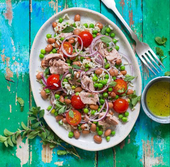 Reissalat auf einem ovalen Teller, darauf Thunfisch aus der Dose, Erbsen, Kirschtomaten und Bohnen
