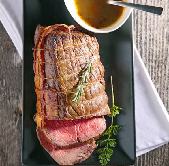 Ganzer Rinderbraten angeschnitten, daneben Portweinsoße in einer Sauciere