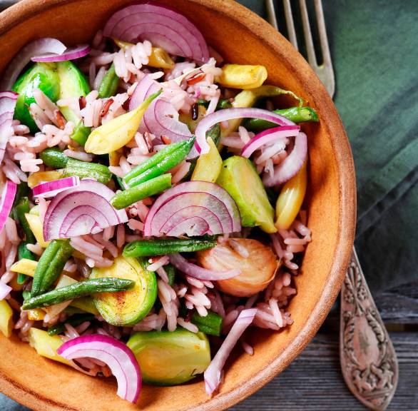 Rosenkohlsalat mit Reis & Bohnen in einer Salatschüssel, daneben Essig-Öl-Dressing