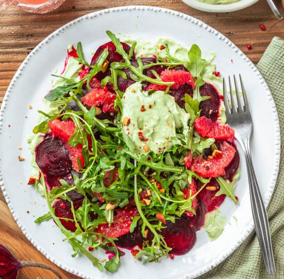 Rote-Bete-Carpaccio mit Grapefruit auf Rucola getoppt von Avocadocreme auf einem Teller