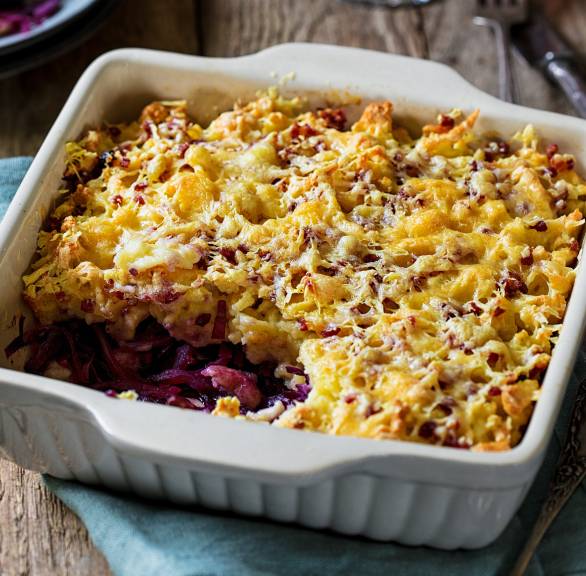 Rotkohl-Spätzle-Auflauf in einer Auflaufform auf einem Holztisch überbacken mit Käse