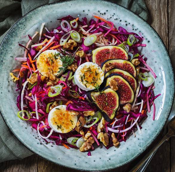 Rotkohlsalat auf einem Teller getoppt von mit karamellisiertem Ziegenkäse, Feigenhälften und Walnüssen