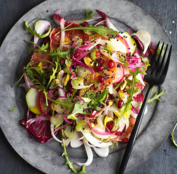 Blutorangen-Fenchel-Salat mit getoppt von Pistazien und Granatapfelkernen angerichtet auf einem Salatteller