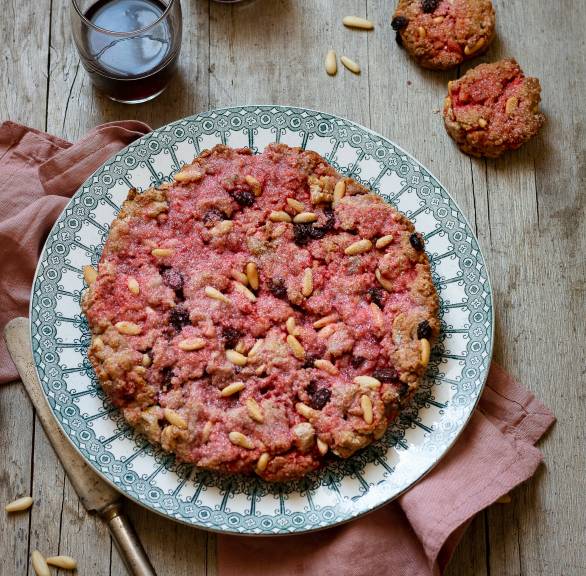 Rosa Kuchen auf einem Kuchenteller getoppt von Pinienkernen