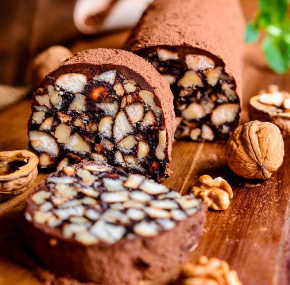 Selbstgemachte Keksrolle mit Kakao, Espresso & Walnuss angeschnitten auf einem Holzbrett