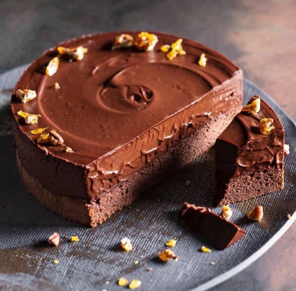 Schokomousse-Torte angeschnitten auf einer Tortenplatte garniert mit Pekannuss-Krokant