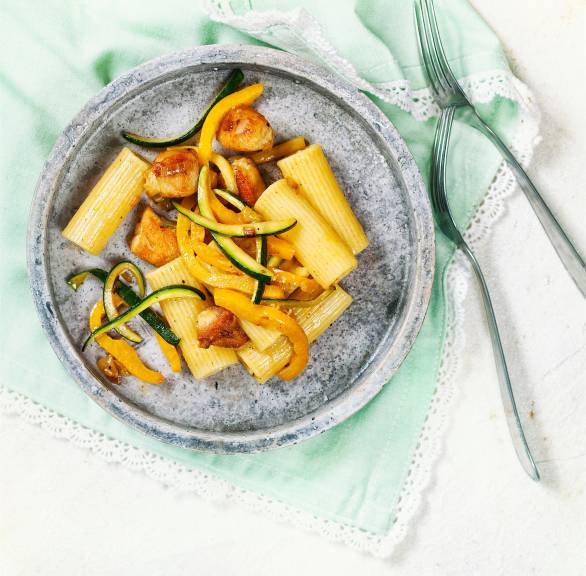 Pastasalat aus Rigatoni auf einem Teller mit gebratenem Hähnchen, Zucchini und Paprika