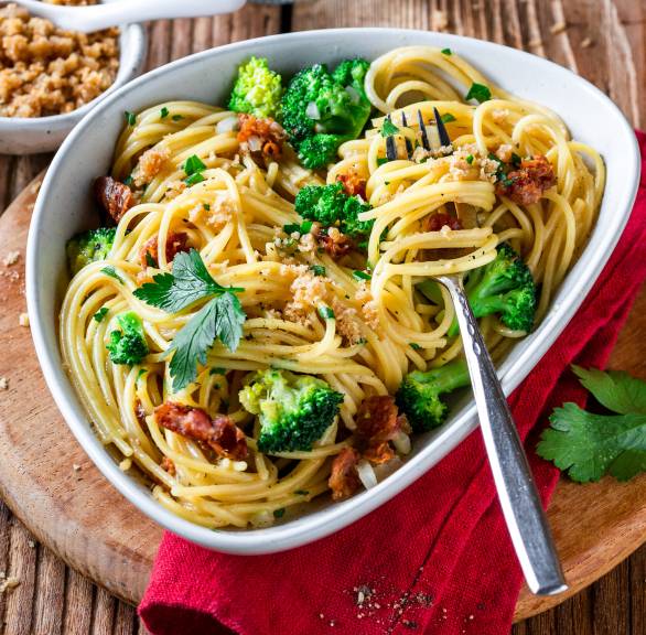Spaghetti mit Brokkoli-Carbonara in einem ovalen, tiefen Teller auf einem Tisch