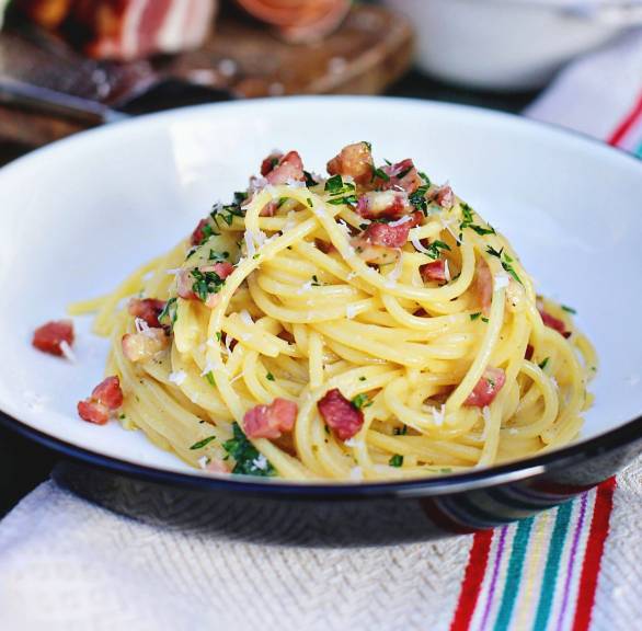 Spaghetti mit Limetten-Carbonara mit Pancetta angerichtet auf einem tiefen Teller