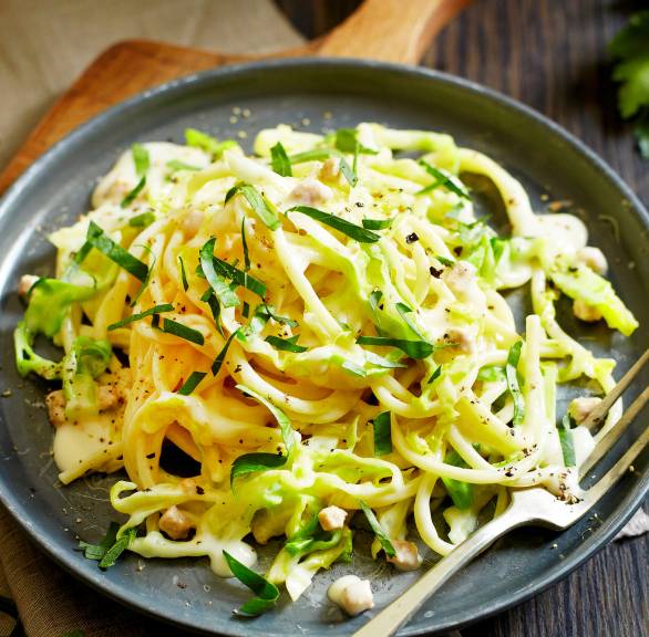 Spaghetti mit Spitzkohl, Speck und Sahnesoße angerichtet auf einem Teller