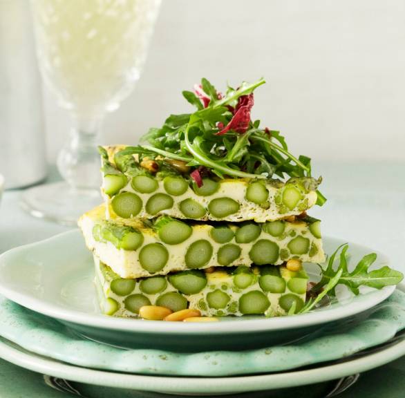 Spargelfrittata mit grünem Spargel in Stücke geschnitten gestapelt auf einem Teller