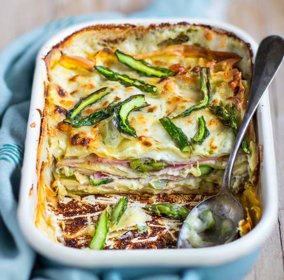 Spargellasagne angeschnitten in einer Auflaufform mit sichtbaren Schichten aus Schinken, Lasagneblättern, grünem Spargel und Sauce
