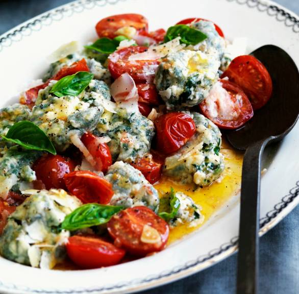 Überbackene Spinat-Ricotta-Nocken mit Tomaten und Käsekruste angerichtet auf einem Teller