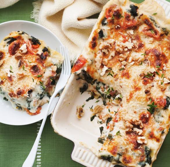 Angeschnittene Spinatlasagne mit Ziegenkäse, Feigen und Walnüssen in einer Auflaufform