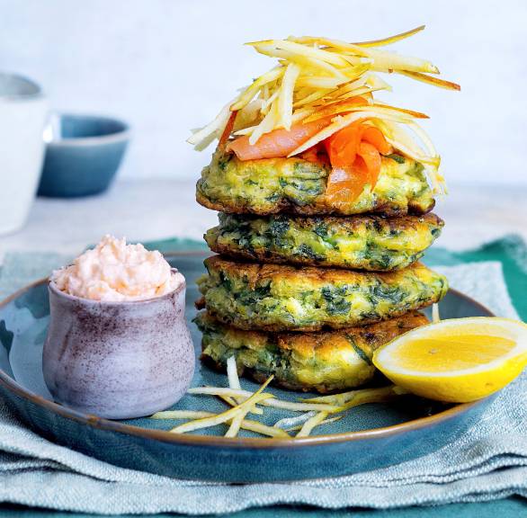 Vier Spinatpuffer gestapelt auf einem Teller, getoppt mit mit Räucherlachs